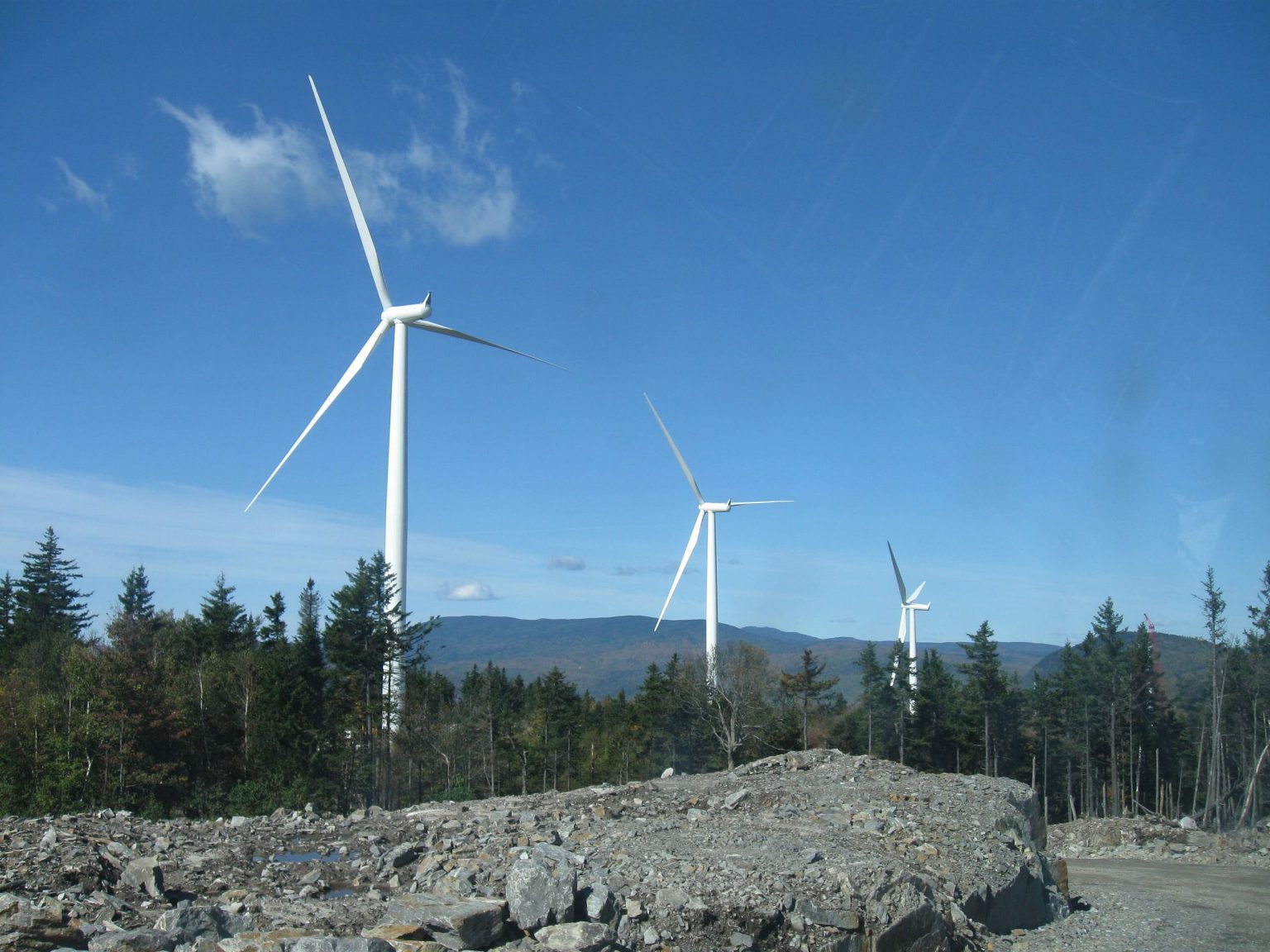 Scenic view of rocky landscape and wind turbine against a clear blue sky.