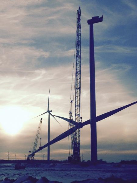 Installation team assembling and erecting a wind turbine at a wind farm site, supporting the growth of renewable energy infrastructure.