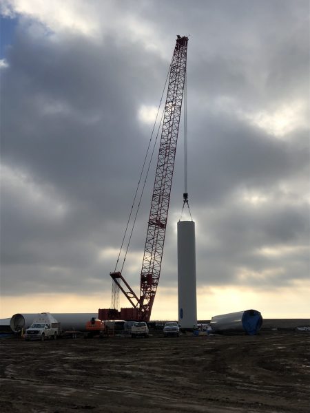 Technicians assembling a wind turbine at a wind farm site, facilitating the growth of renewable energy infrastructure.