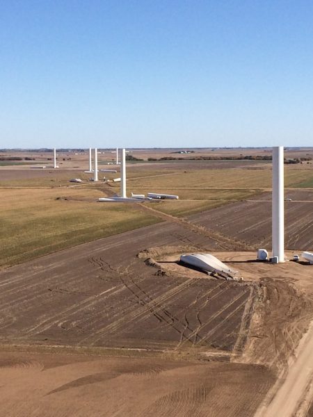 Technicians installing a wind turbine at a wind farm site, contributing to the expansion of renewable energy infrastructure.