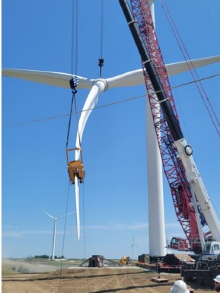 Installation team working on a wind turbine at a wind farm site, contributing to the development of renewable energy resources.
