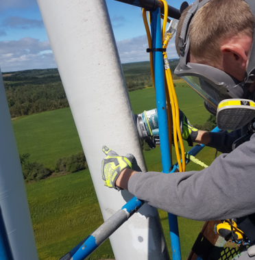 Technician utilizing rope access for maintenance on a wind turbine tower, ensuring operational efficiency and safety.